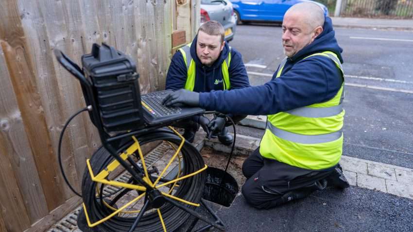 A drainage engineer in Southampton using a CCTV inspection camera to check underground pipes, with a monitor displaying live footage of the drain interior.