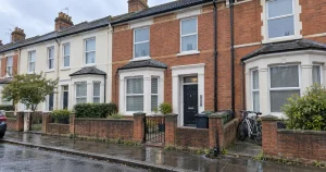 Exterior of a Southampton terraced HMO after rain, with shared bins, bicycles and water pooling beside the rainwater gully.