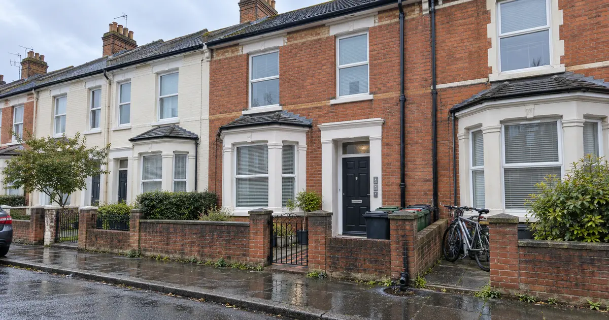Exterior of a Southampton terraced HMO after rain, with shared bins, bicycles and water pooling beside the rainwater gully.